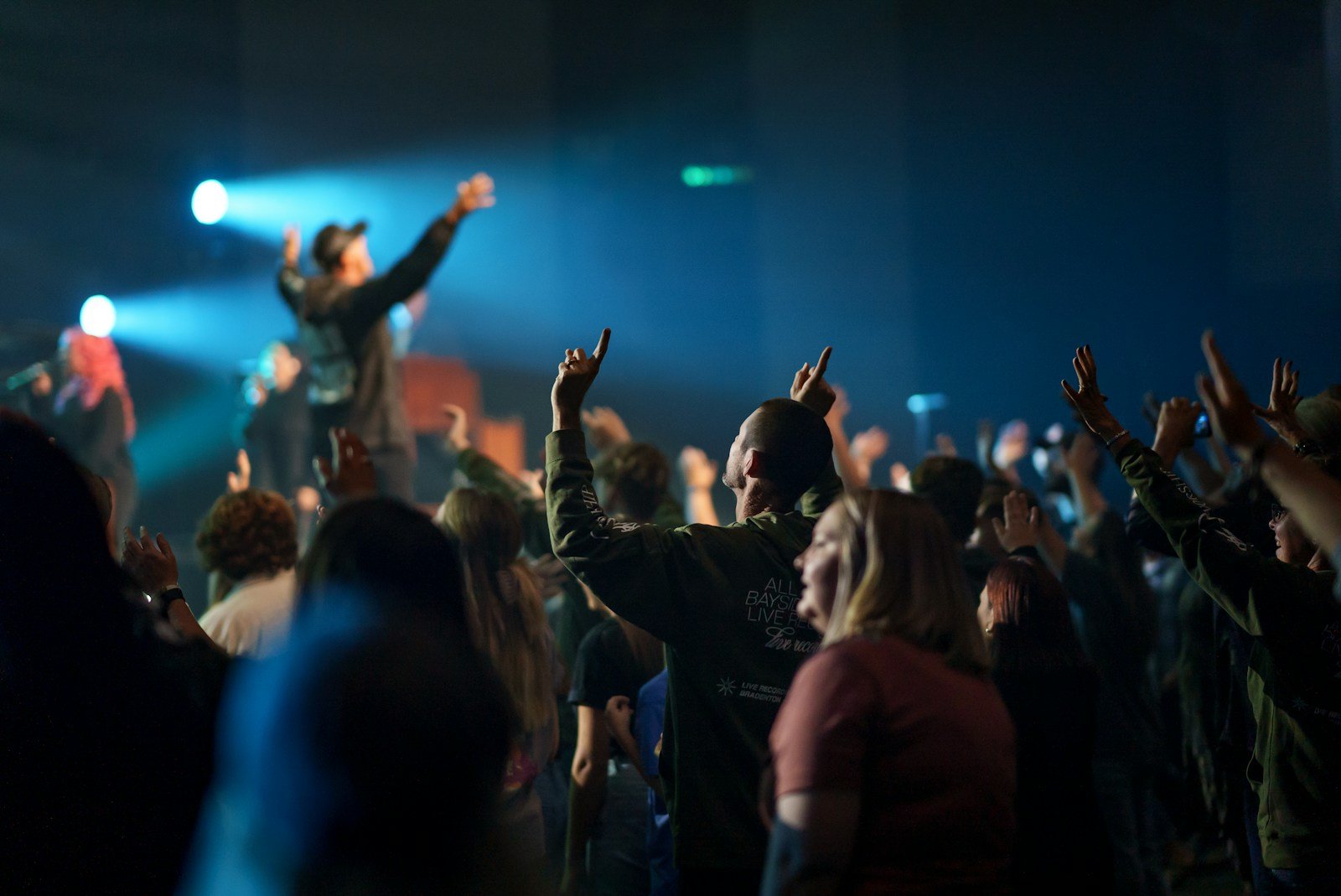 Photo by NATHAN MULLET a crowd of people at a concert raising their hands in the air
